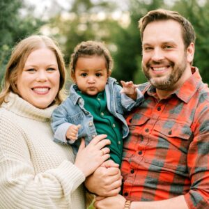 Lindsay and Bill posing with their toddler outside.